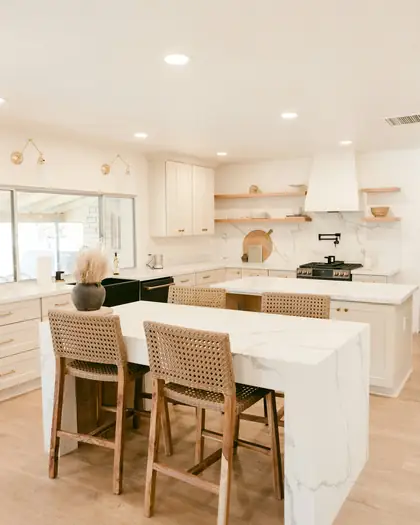Bright kitchen with a white marble island and woven bar stools