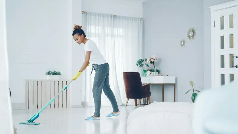 Cleaner mopping the floor of a bright white living room