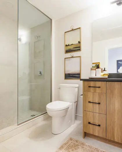 Modern bathroom with a wooden vanity, round mirror and glass shower