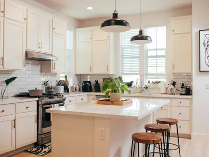 Newly finished white kitchen with an island, pendant lights and bar stools